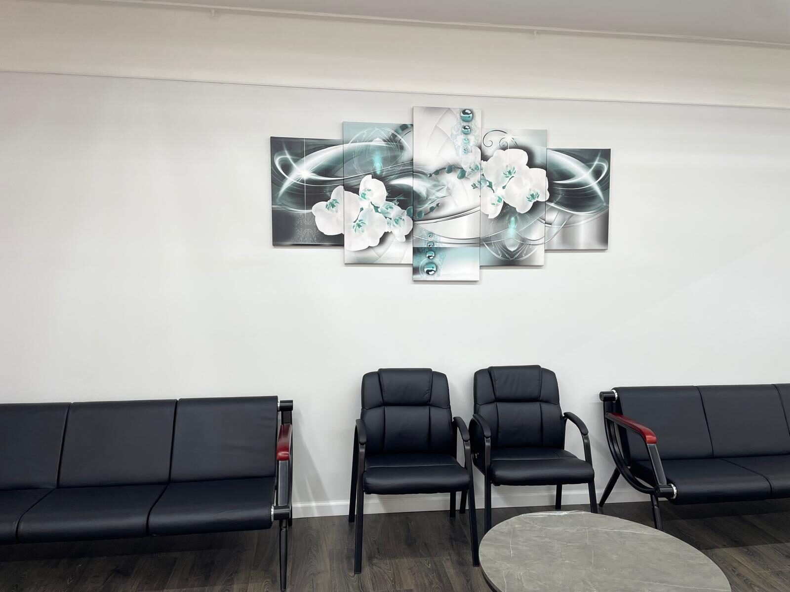The waiting area at Threading Heaven — black leather seating with abstract wall art on Post Ave in Westbury